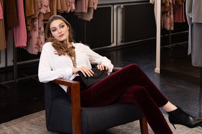 Junge Frau sitzend auf Sessel in MXM Outfit